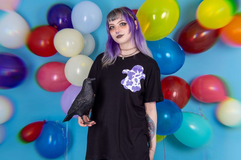 Alternative purple haired white model posing in front of a balloon background for small fashion business Grunge Monkey.