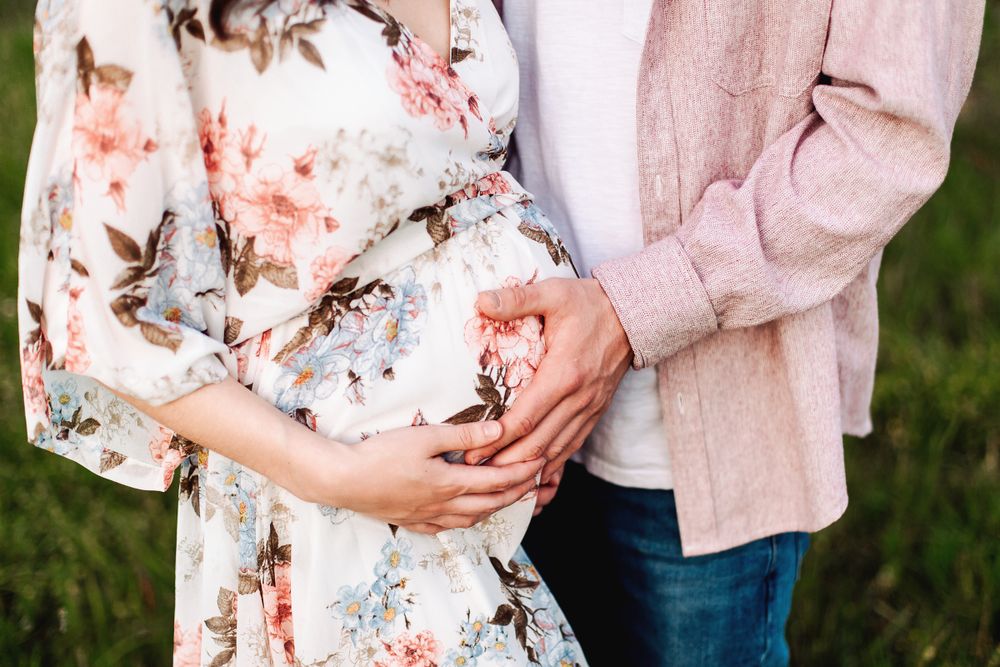 close up of mom to be and her partners hands holding her pregnant belly