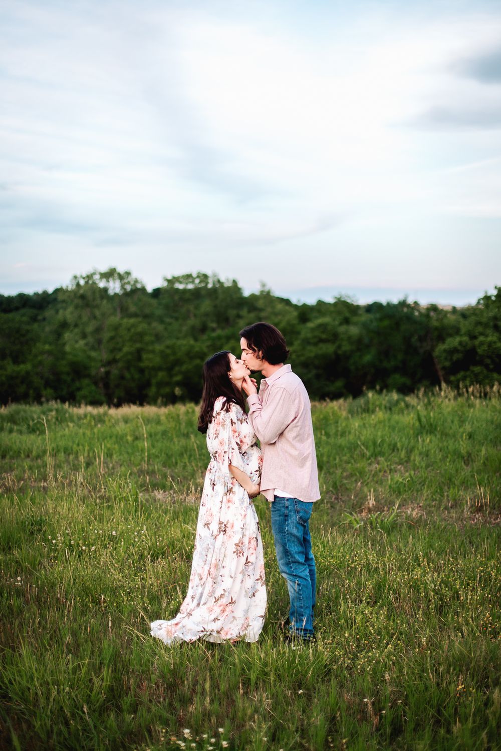 man and woman share a kiss during their maternity portrait session