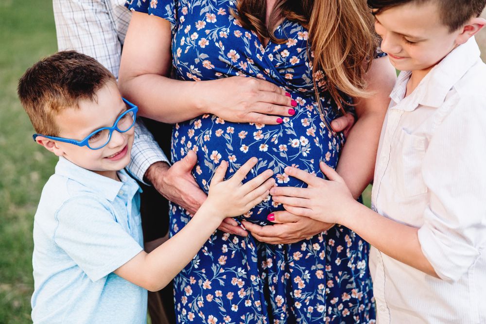 family touches moms pregnant belly during maternity session