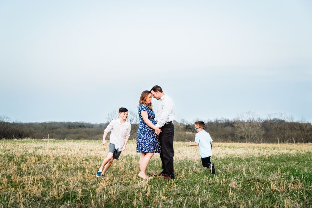 mom and dad holding hands while 2 boys run in circles around them