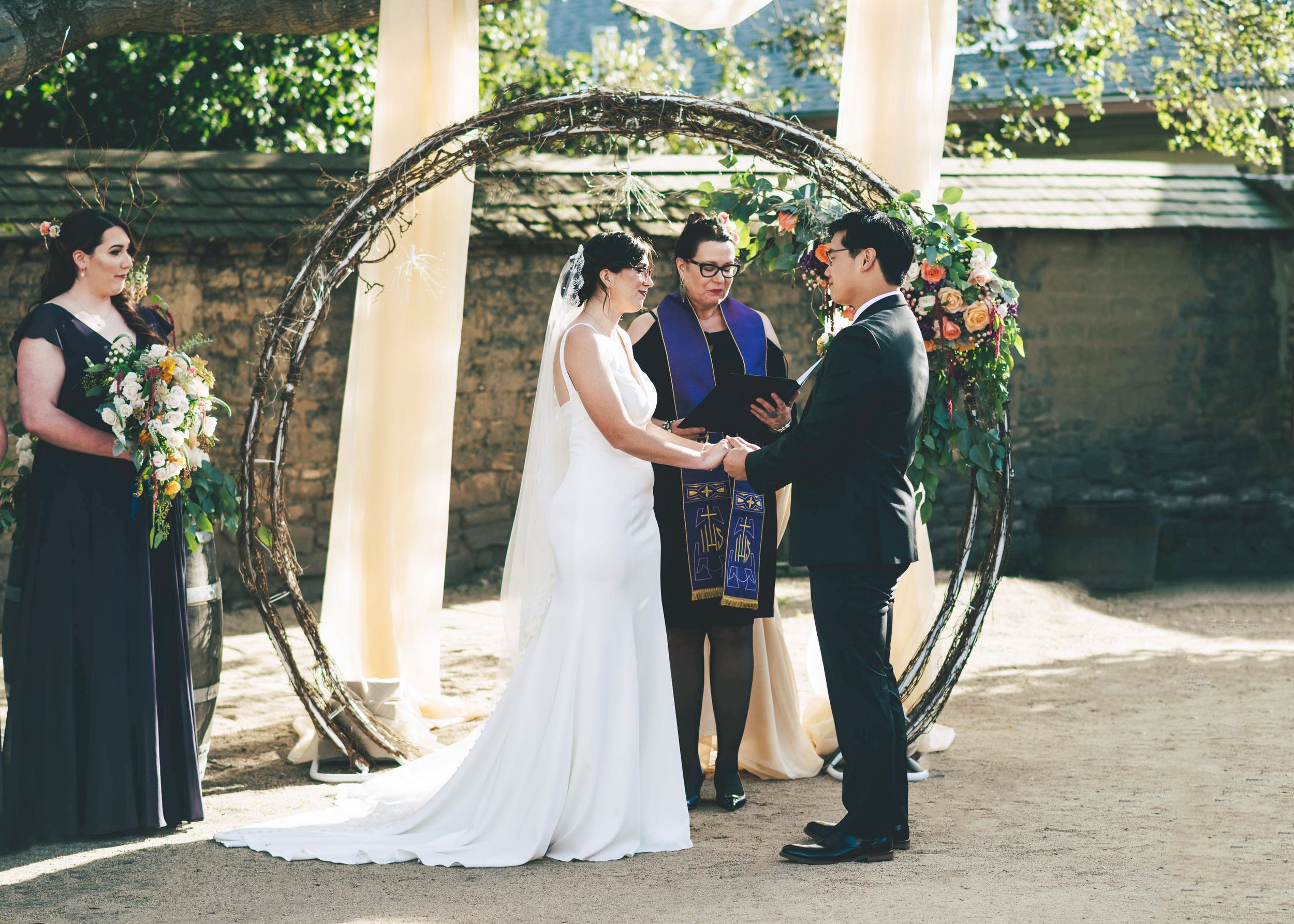 bride and groom in front of circular wedding arch