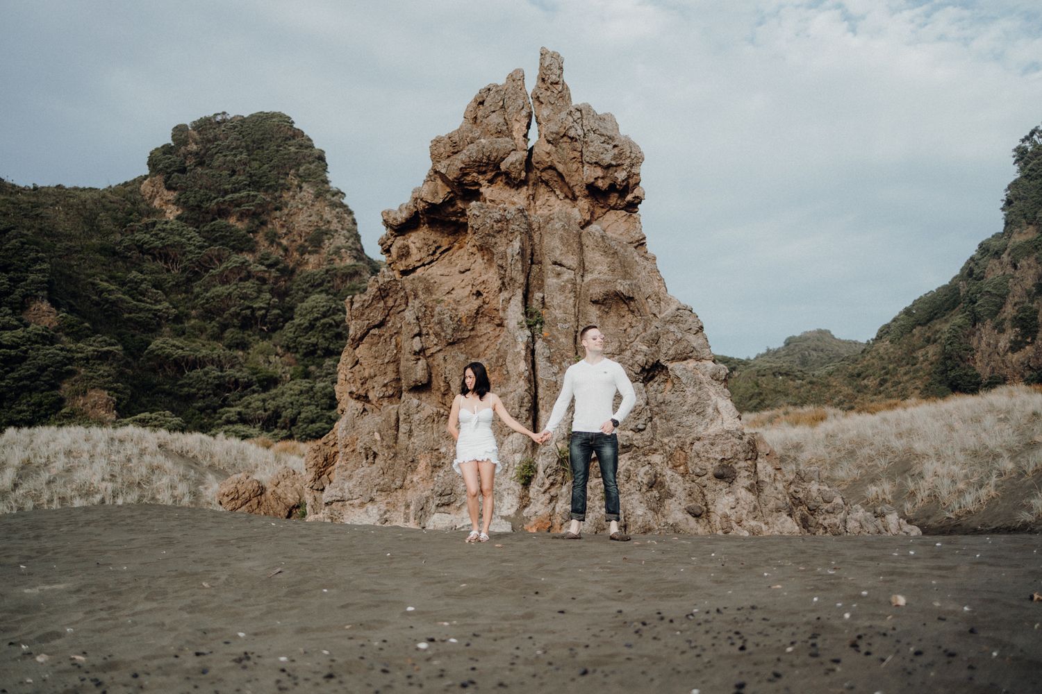 A couple in Karekare Beach Rock for their post-wedding photoshoot with Apertured Media-Auckland Wedding Photographer.