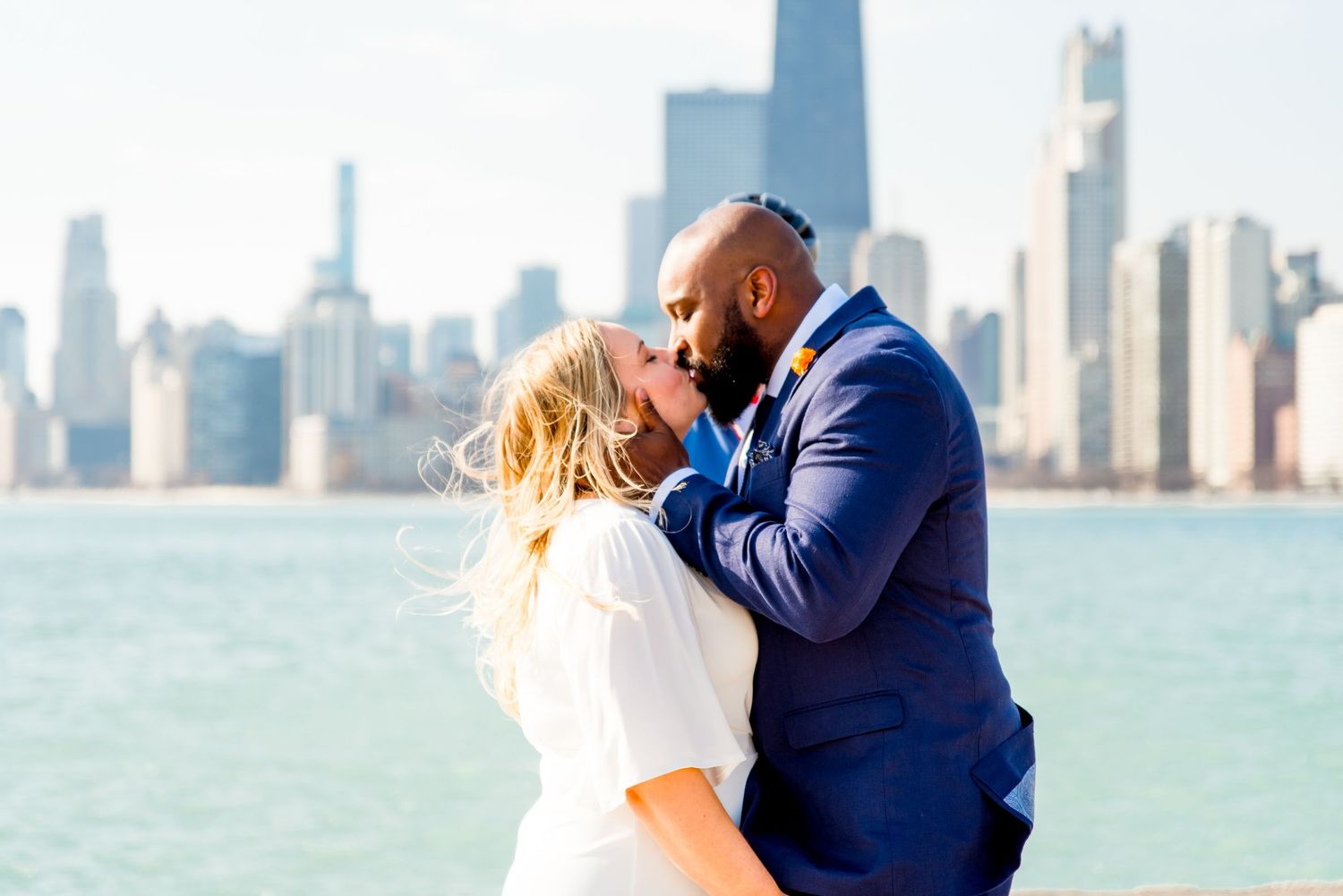 blonde woman and man with beard in navy suit kissing on pier at north avenue beach after chicago elopement