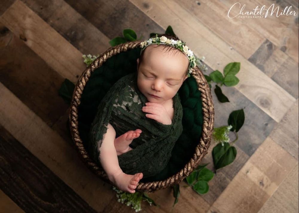 baby girl in emerald wrap and greenery
