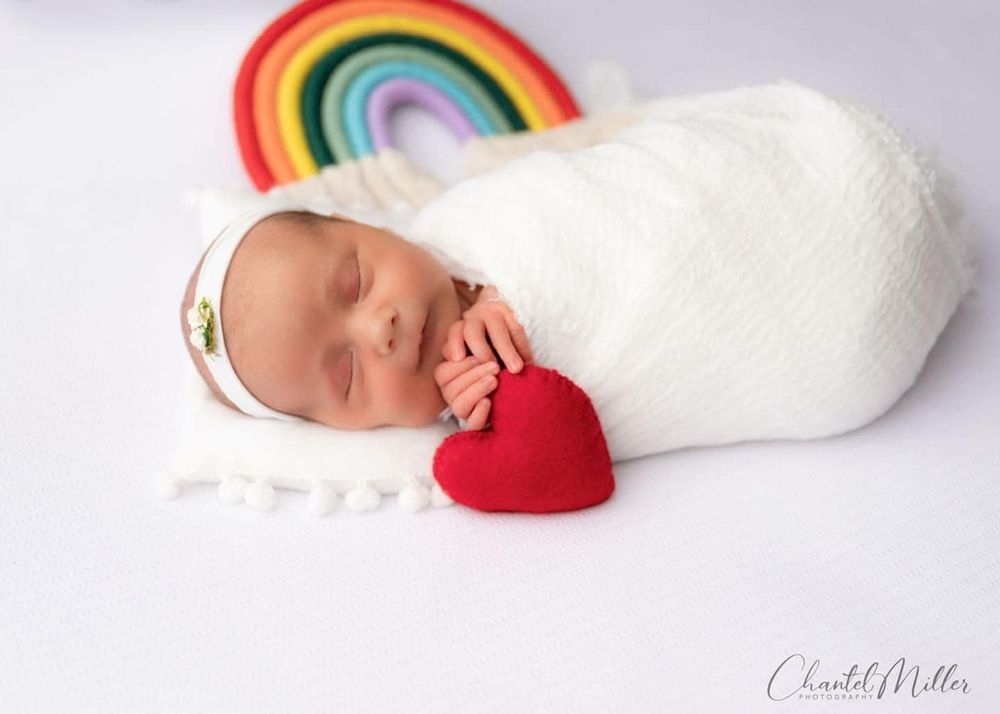 rainbow baby sleeping holding heart