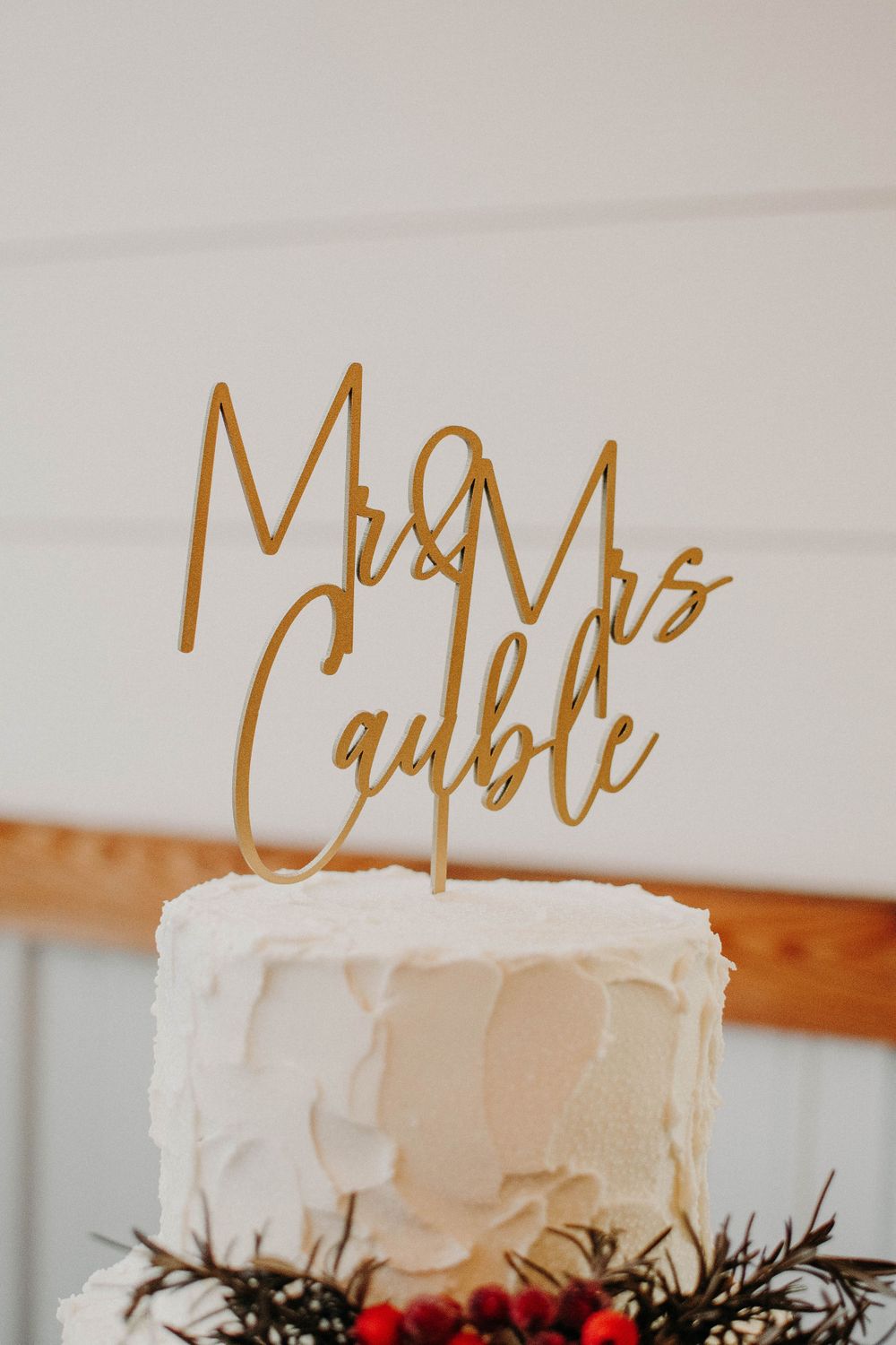White frosted wedding cake with gold Mr & Mrs Cauble metallic cake topper.
