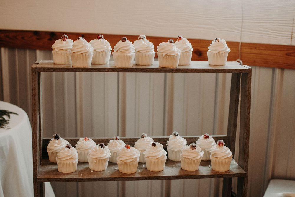 Display of white frosted cupcakes arranged on modern industrial metal shelving.