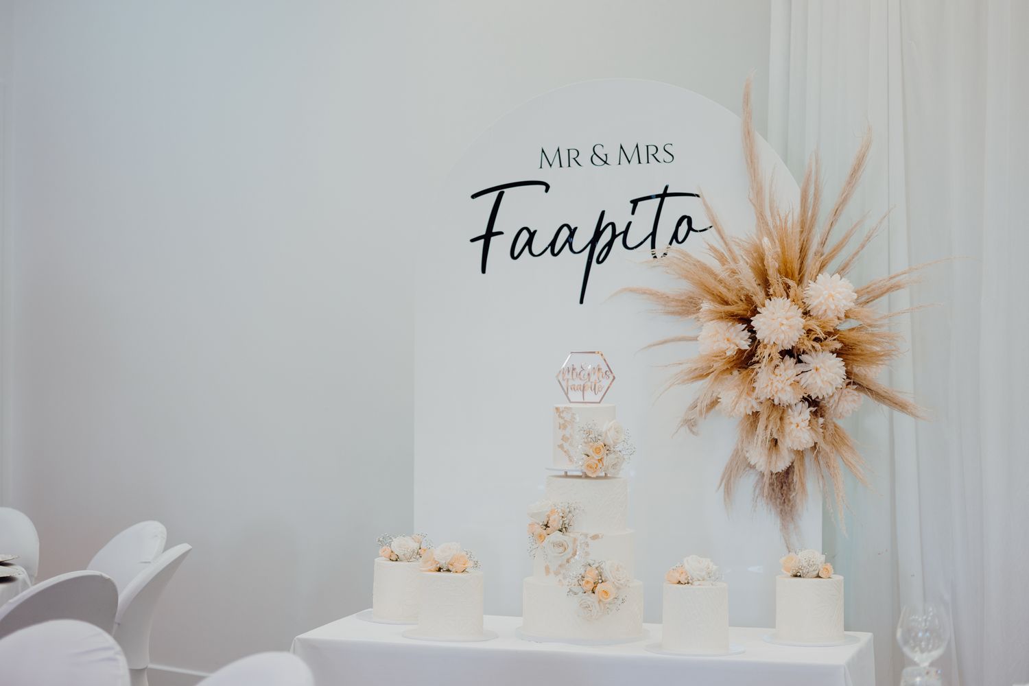 Modern wedding dessert display with pampas grass decor and 'Mr & Mrs Faapito' signage.
