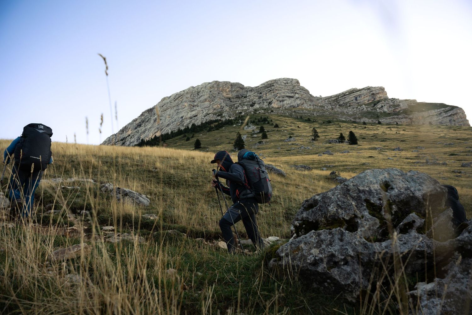 Silhouettes of hikers ascending a rocky mountain slope at dusk.