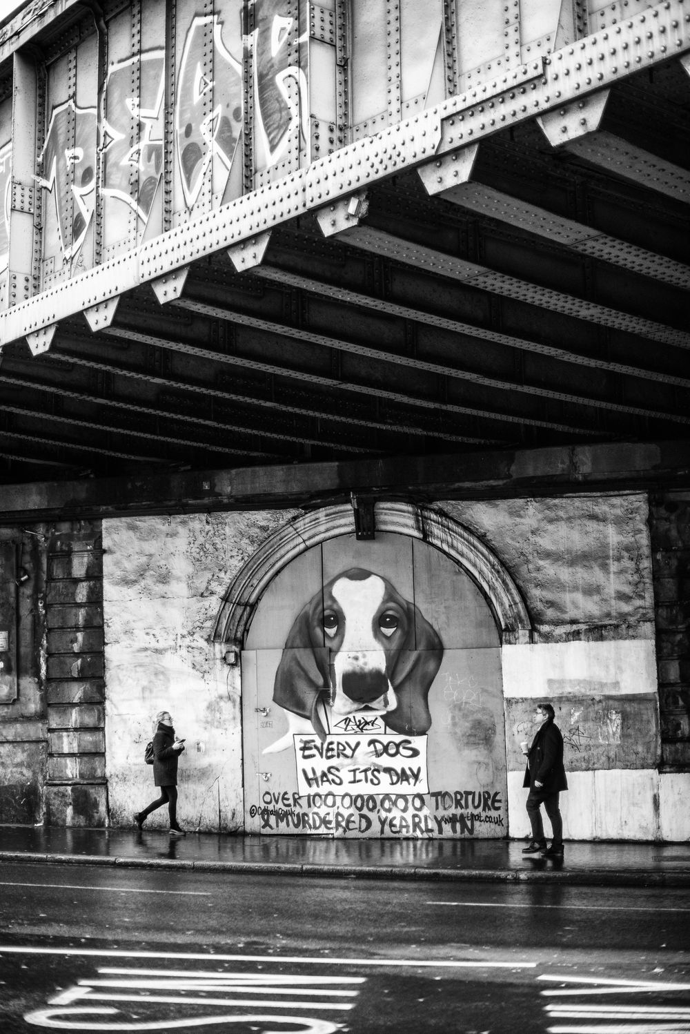 Grafitti under a bridge in London of a beagle with two people approaching