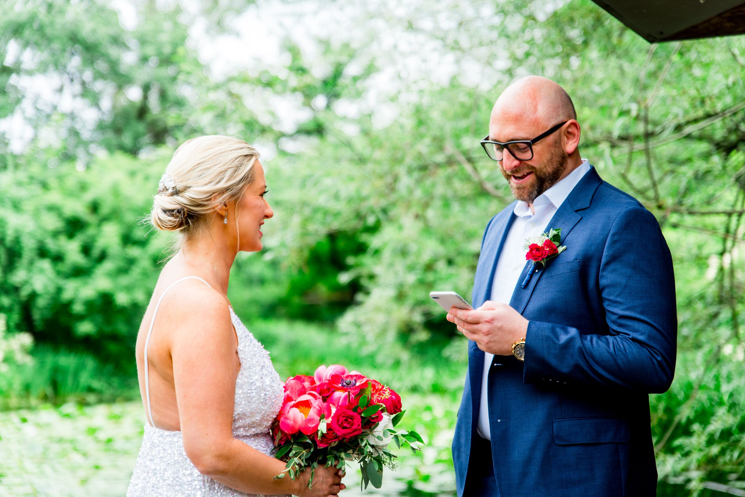 couple laughing reading vows at Alfred Caldwell Lily Pool in Lincoln Park Chicago