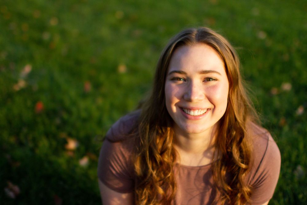 Outdoor portrait in warm sunlight with natural autumn background.