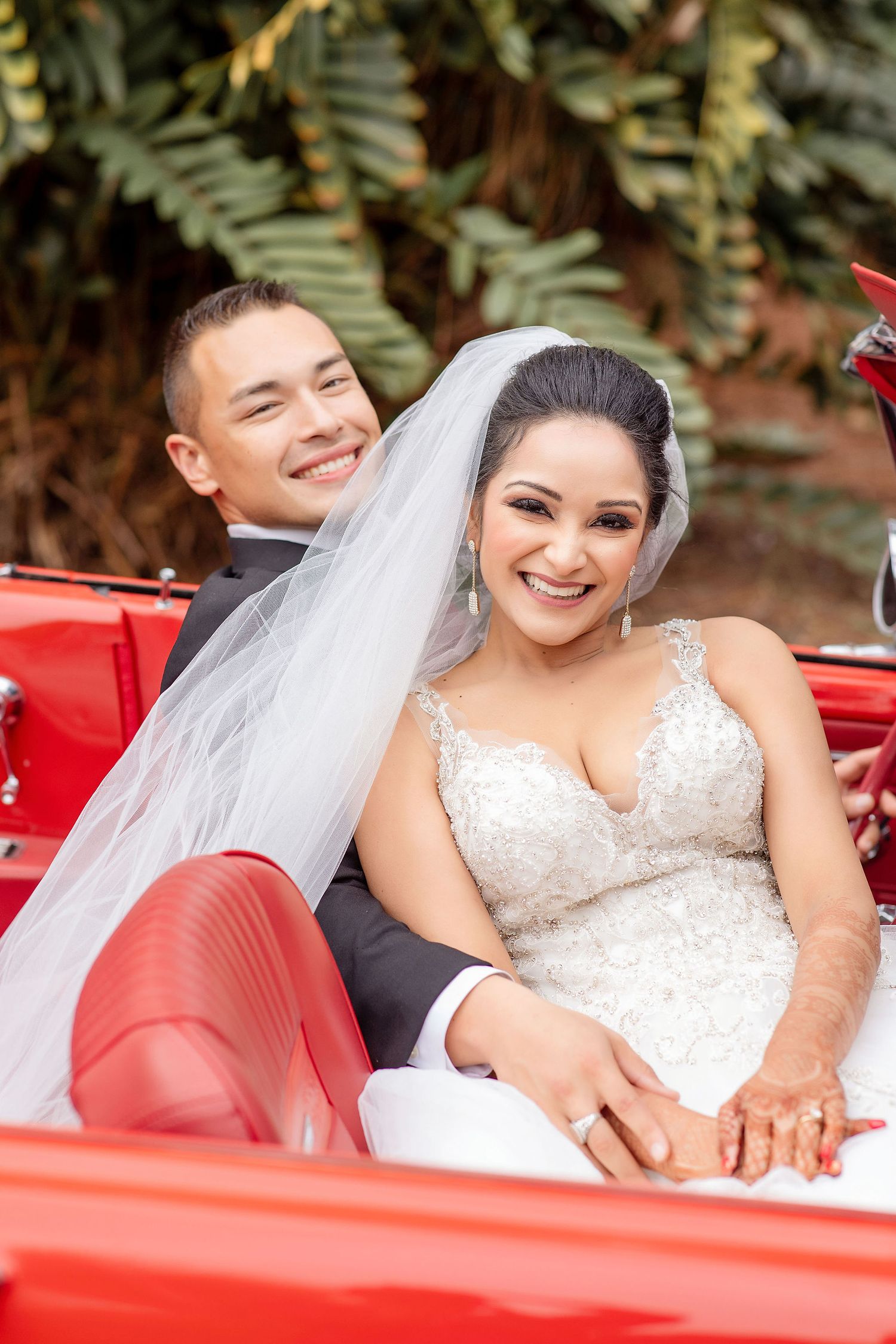 Groom and bride with a red car on a background at the Powel Crosley Estate