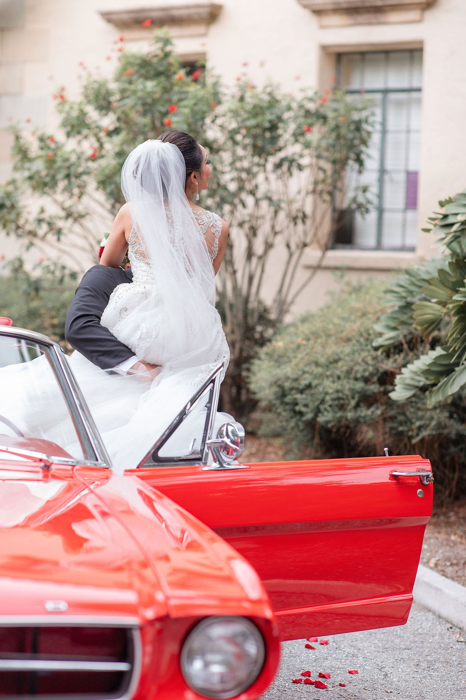 bride and groom with a red car on a background at the Powel Crosley Estate