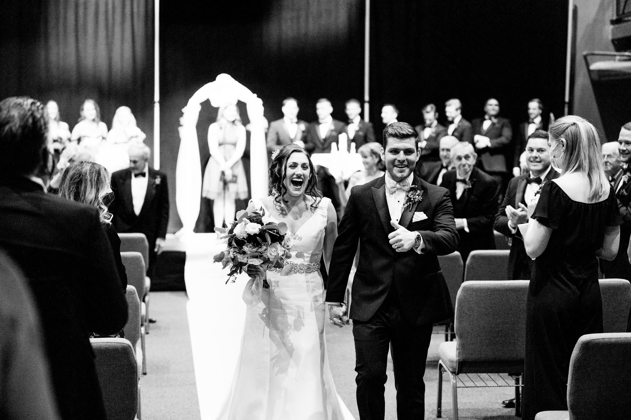 black and white portait of bride and groom walking down the aisle after ceremony