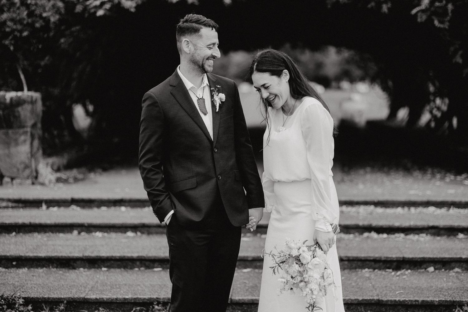 Black and white portrait of a happy couple sharing a candid moment on stone steps.