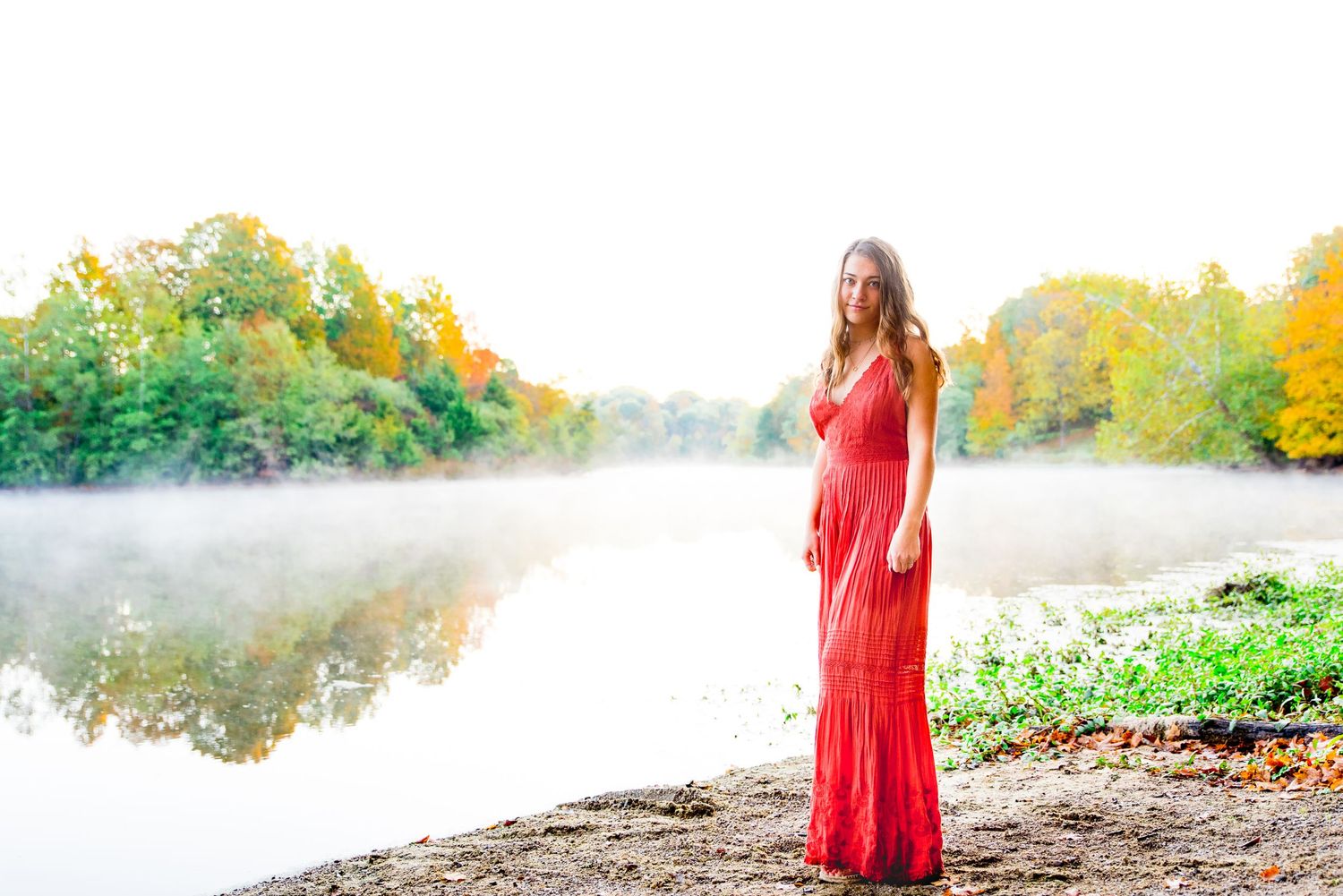 high school senior pictures in orange jump suit at a foggy lake with fall colored trees in Chicago