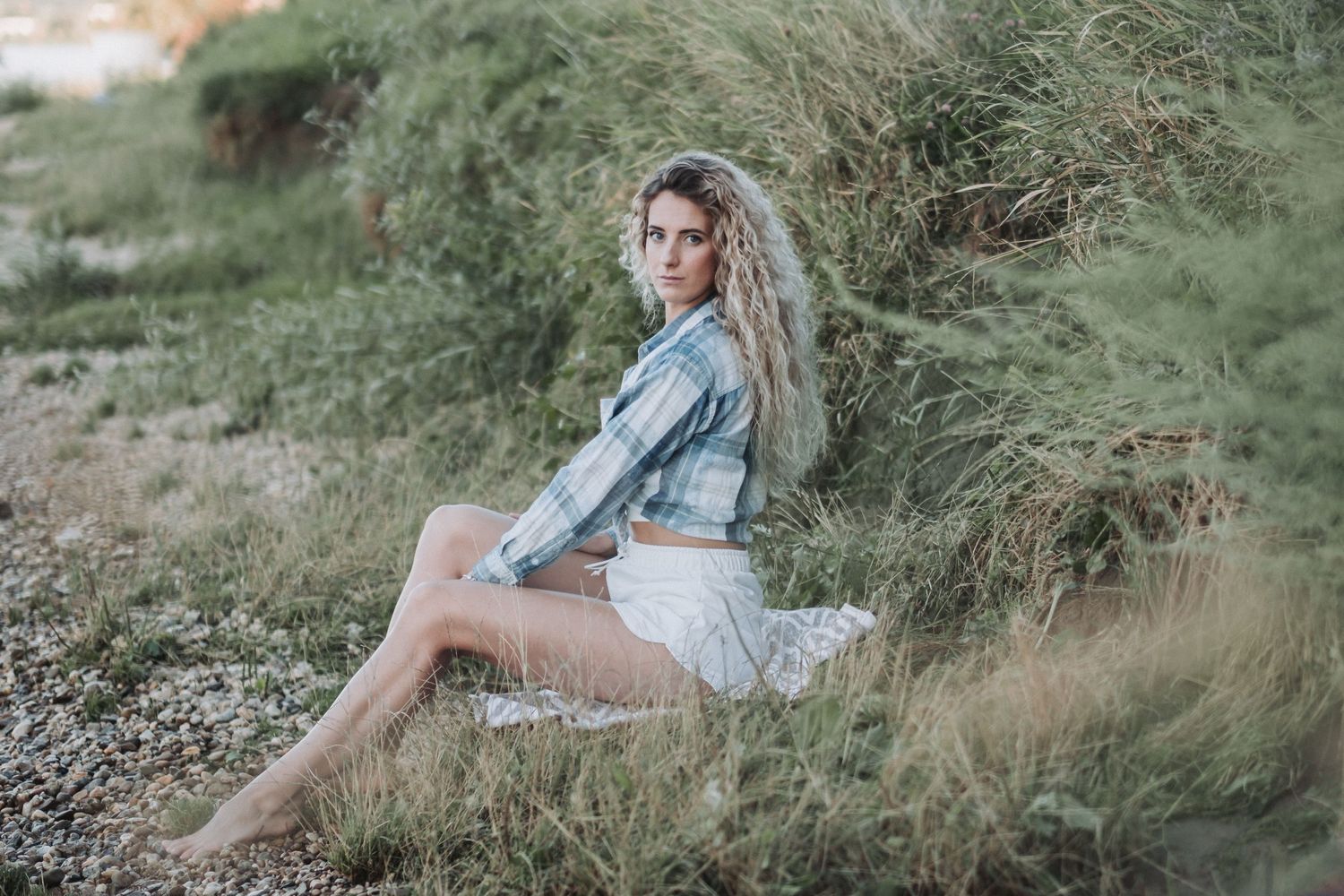 Lifestyle fashion photography on grassy coastal hillside at sunset.