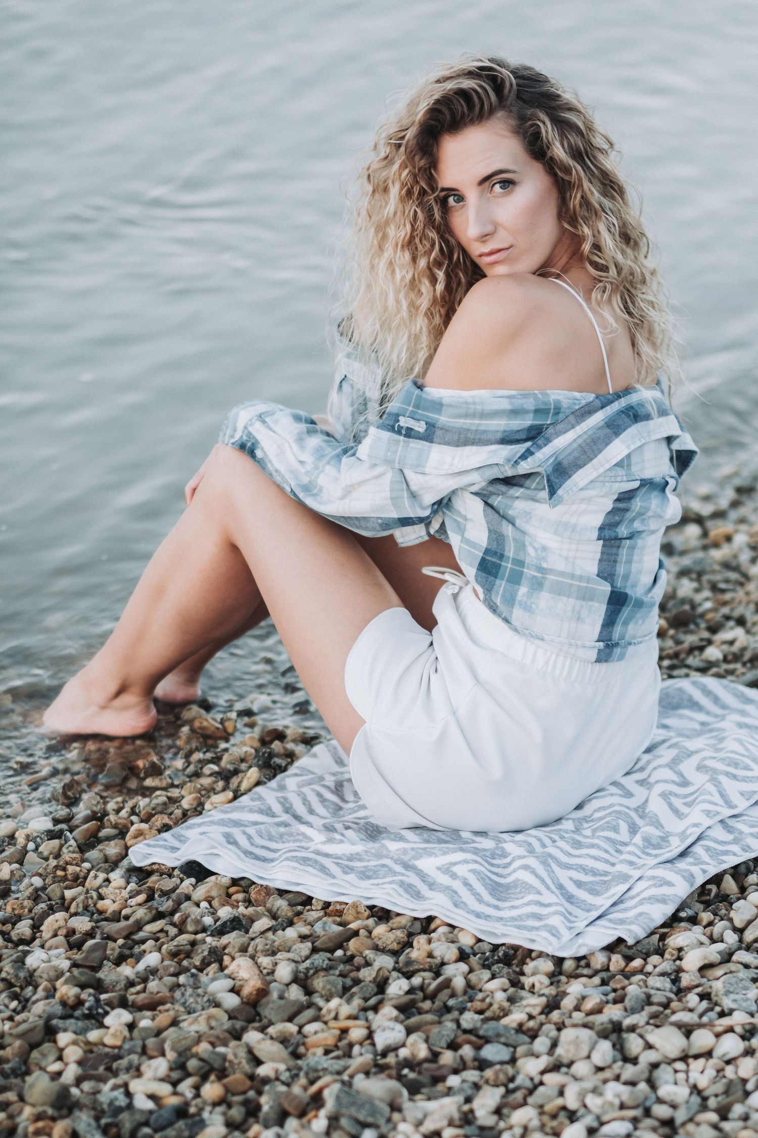 Beachside summer portrait on patterned blanket with casual plaid and white outfit.