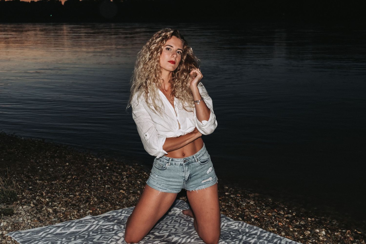 Evening portrait session on rocky beach with dramatic water backdrop.