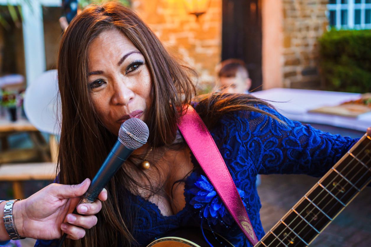 mother of the bride singing at wedding reception with guitar in hand.