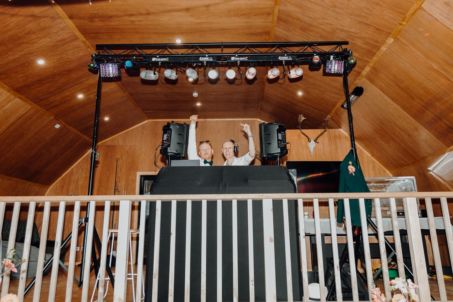 Event lighting rig and sound equipment mounted above white railing at venue.
