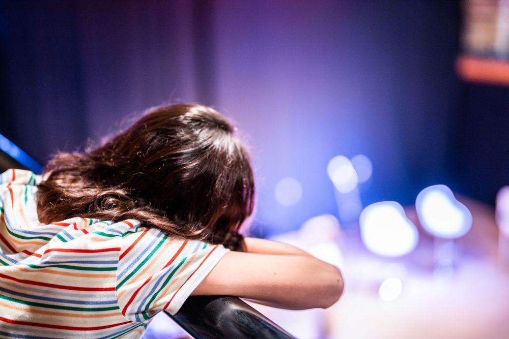 young girl gazing at theatre stage from the gallery at surrey event photography shoot cranleigh arts centre