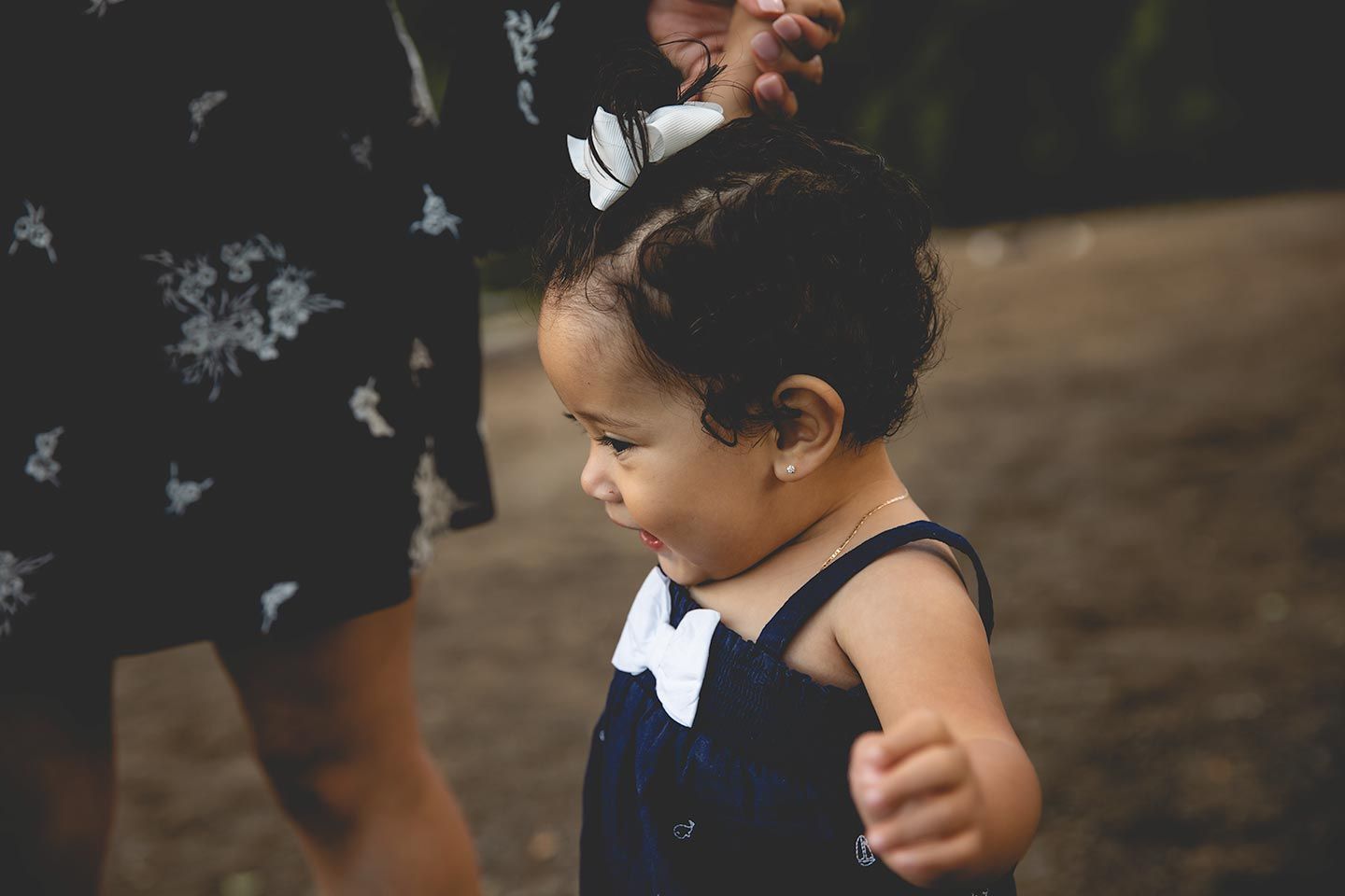 1 year old girl holding her mom's hand to walk on the beach