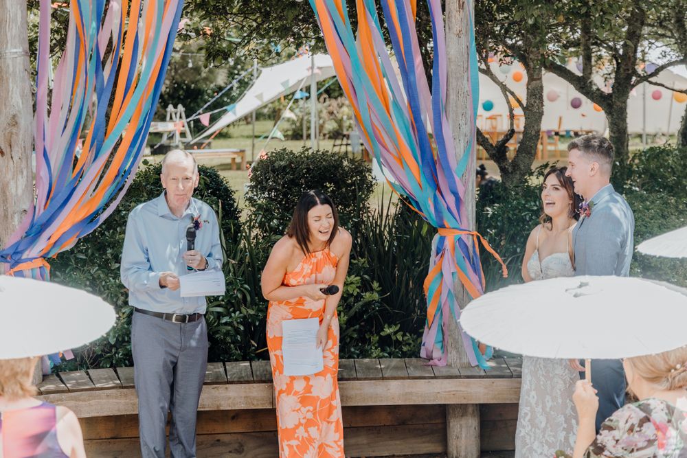 Casual outdoor wedding gathering with colorful streamers and white tables.