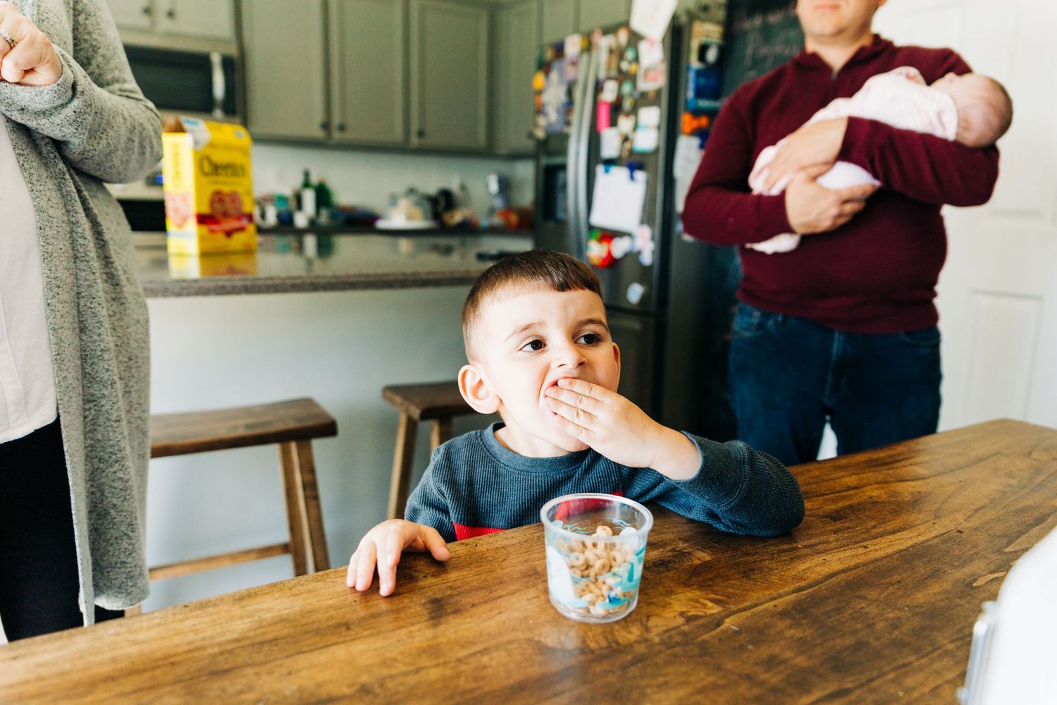 A young boy eating Cheerios while his parents watch