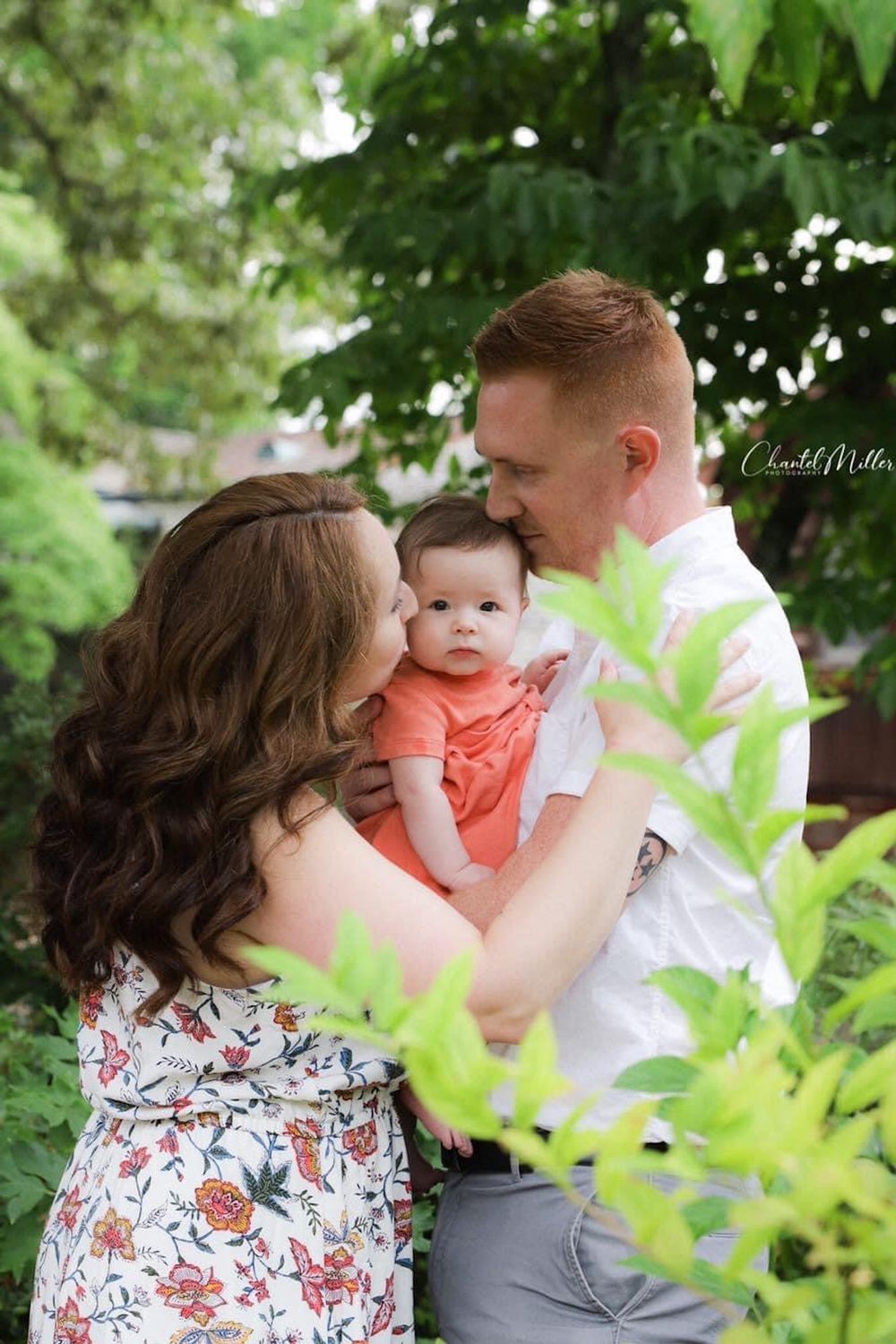 mom and dad kissing baby on forehead