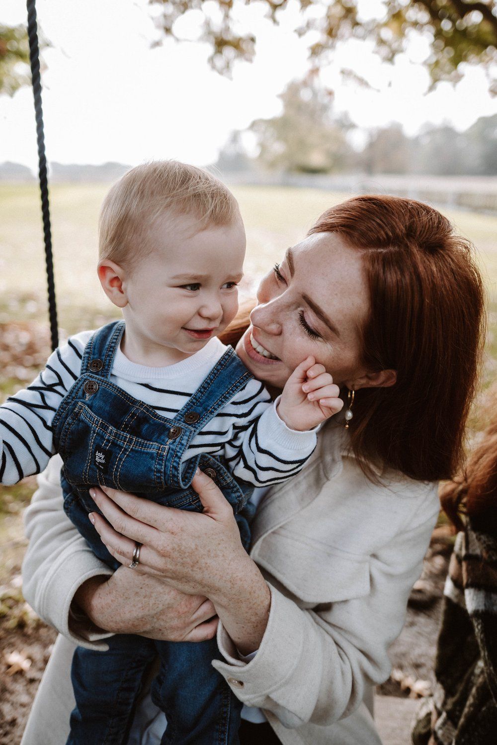Candid outdoor autumn portrait showing playful moment and laughter during intimate family photo session in warm sunlight.