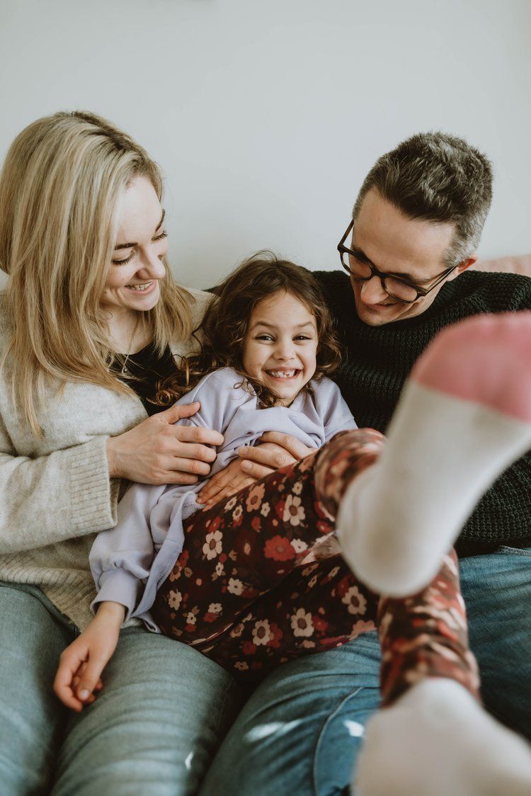 Happy family relaxing and laughing together on couch in cozy living room during casual weekend at home.