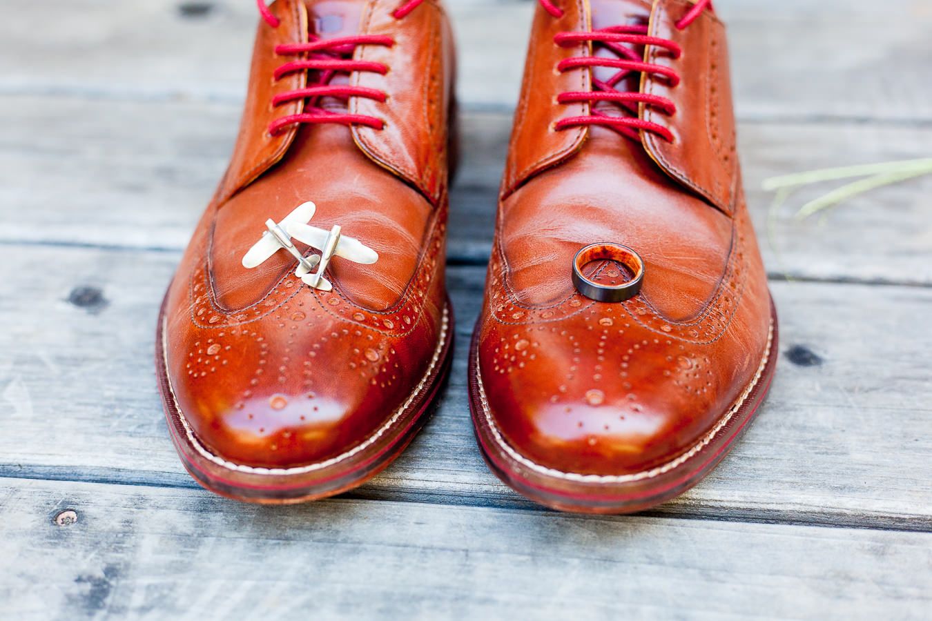 airplane cufflinks and male wedding band on top of grooms wedding shoes