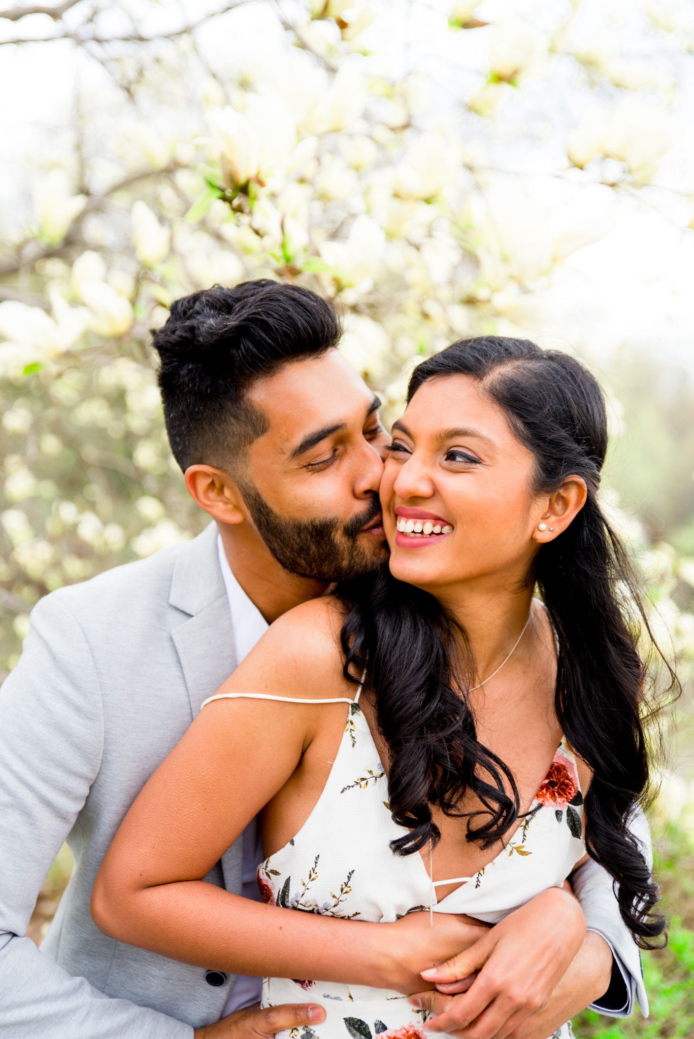 Young couple laughing together under yellow magnolia tree at Central Park engagement photos