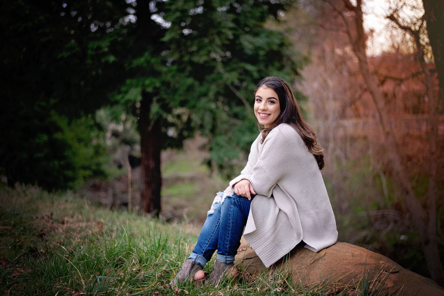 High School Senior girl in Andrews park sitting on a rock.