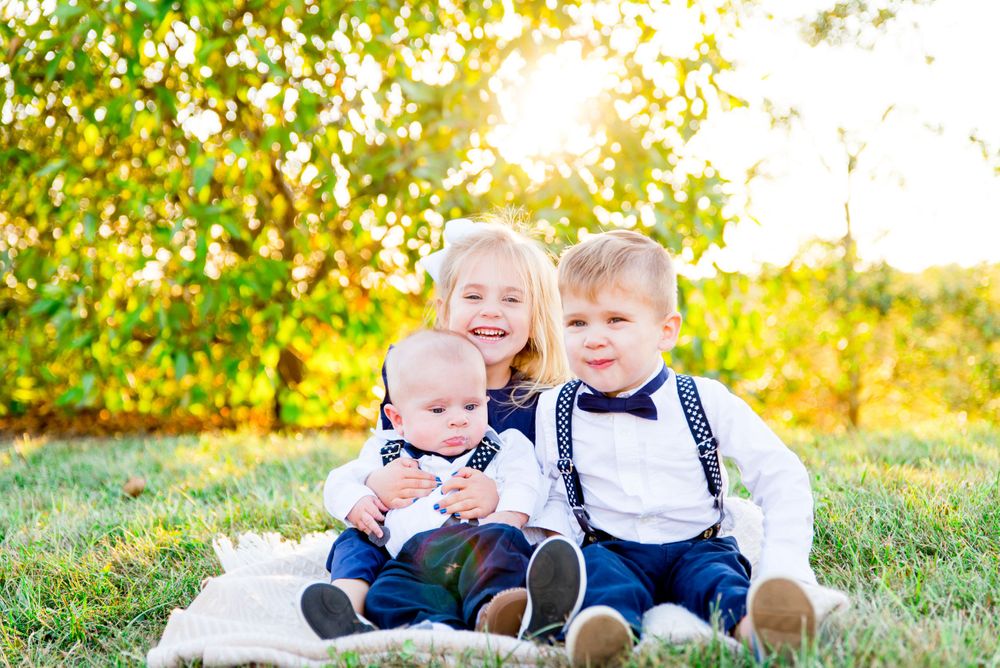little girl laughing with two young brothers at sunset in Chicago Park