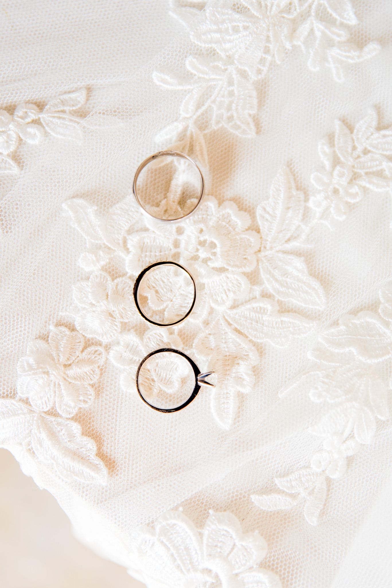 three wedding bands on a white lace veil for fall November wedding in Chicago