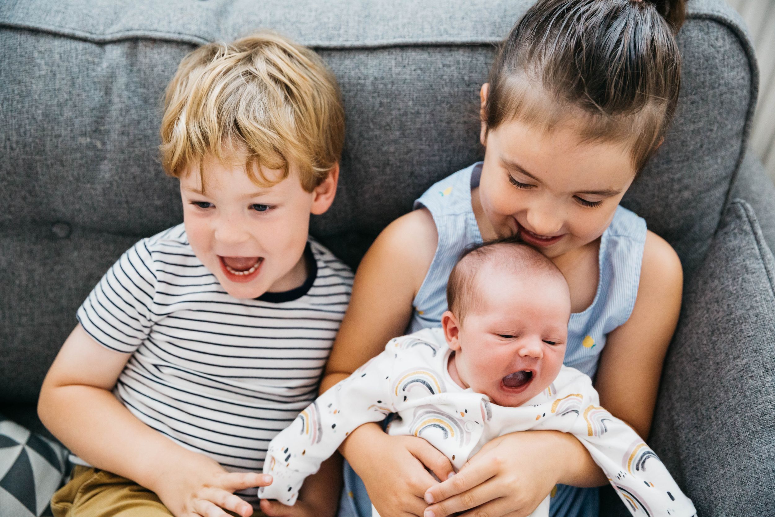 older siblings cuddling with new baby sister