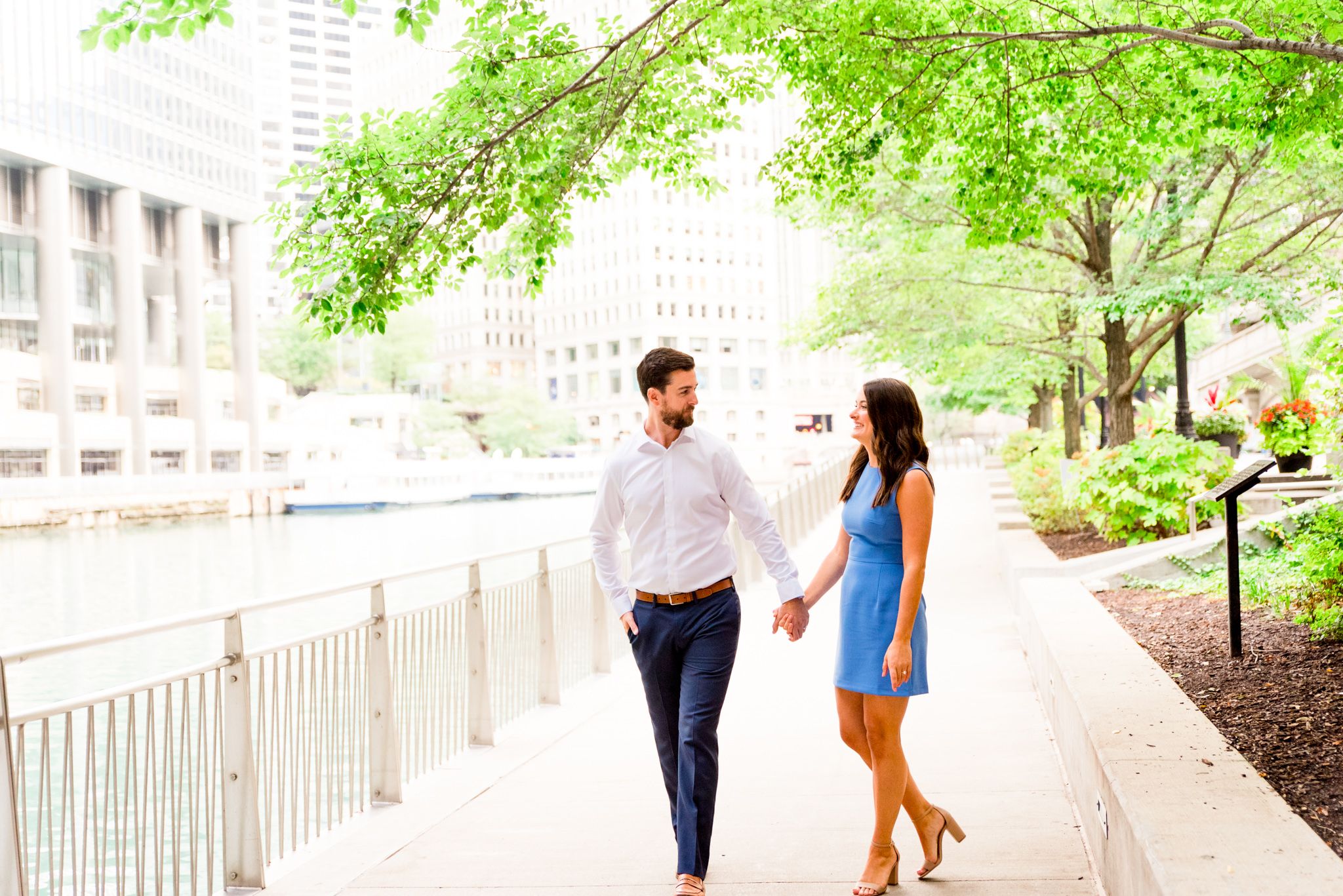 woman in blue dress twirling around with her fiance in white shirt for sunrise chicago engagement pictures