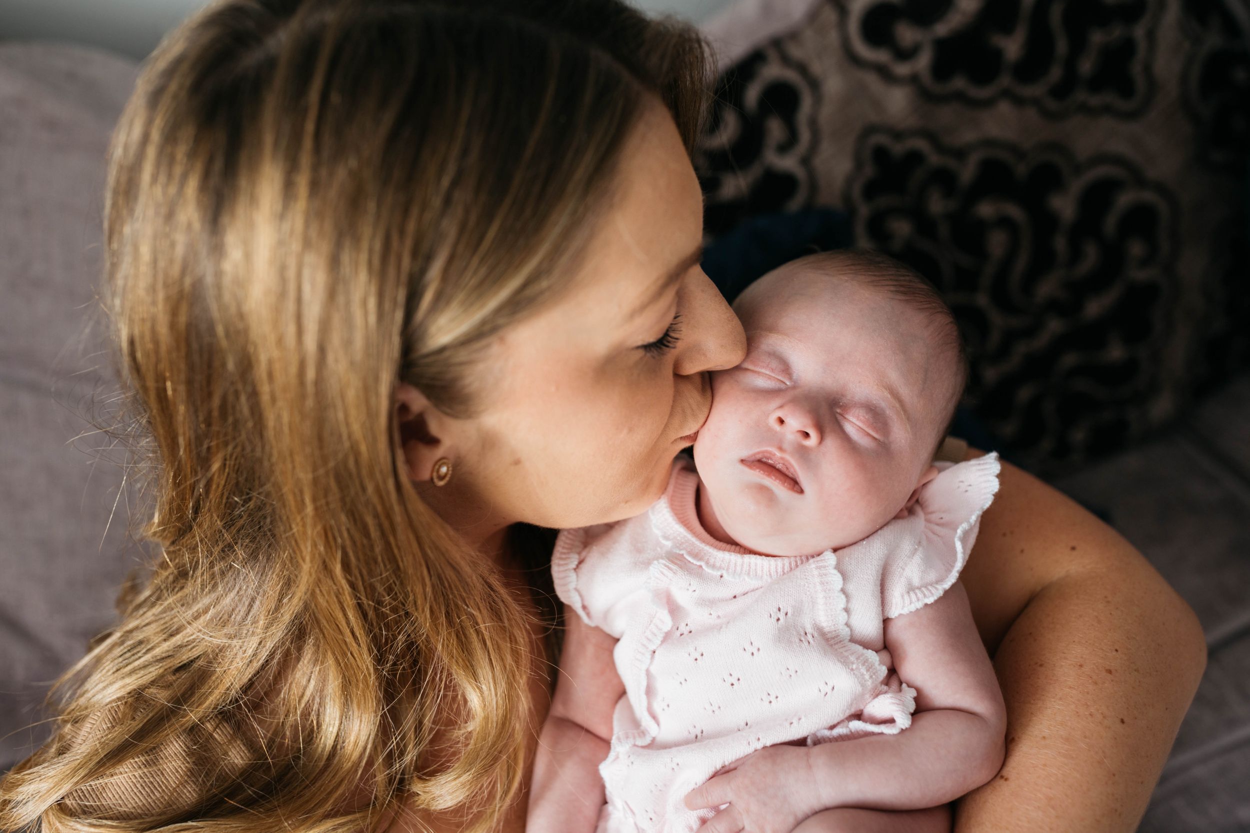mum kissing her newborn baby daughter on cheek