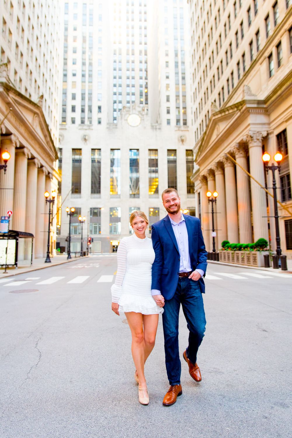 man and woman holding hands smiling walking in front of Chicago Board of Trade empty street