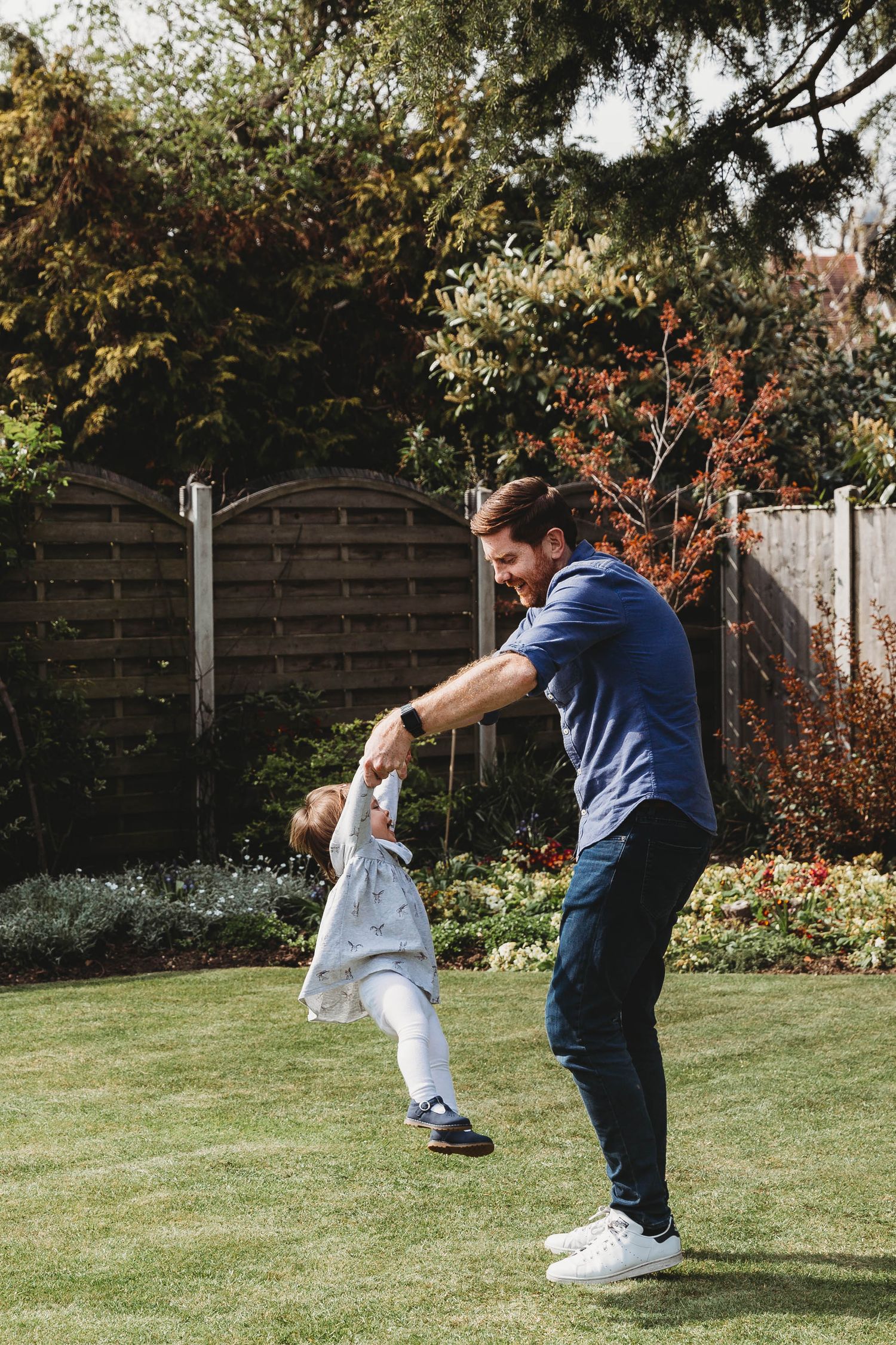 dad twirling with toddler daughter in garden