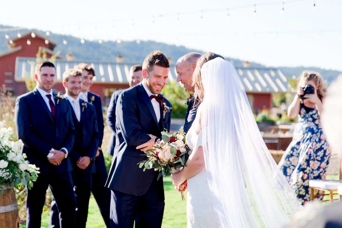 groom in navy suit shaking father of bride's hand and laughing