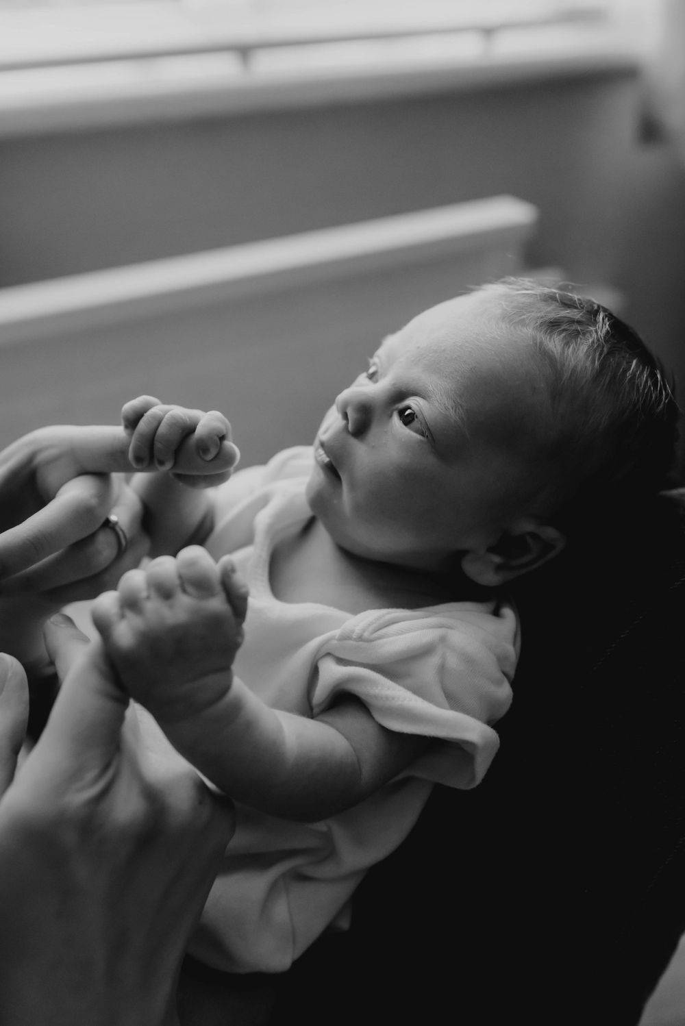 Black and white portrait of a peaceful newborn baby lying on their back.