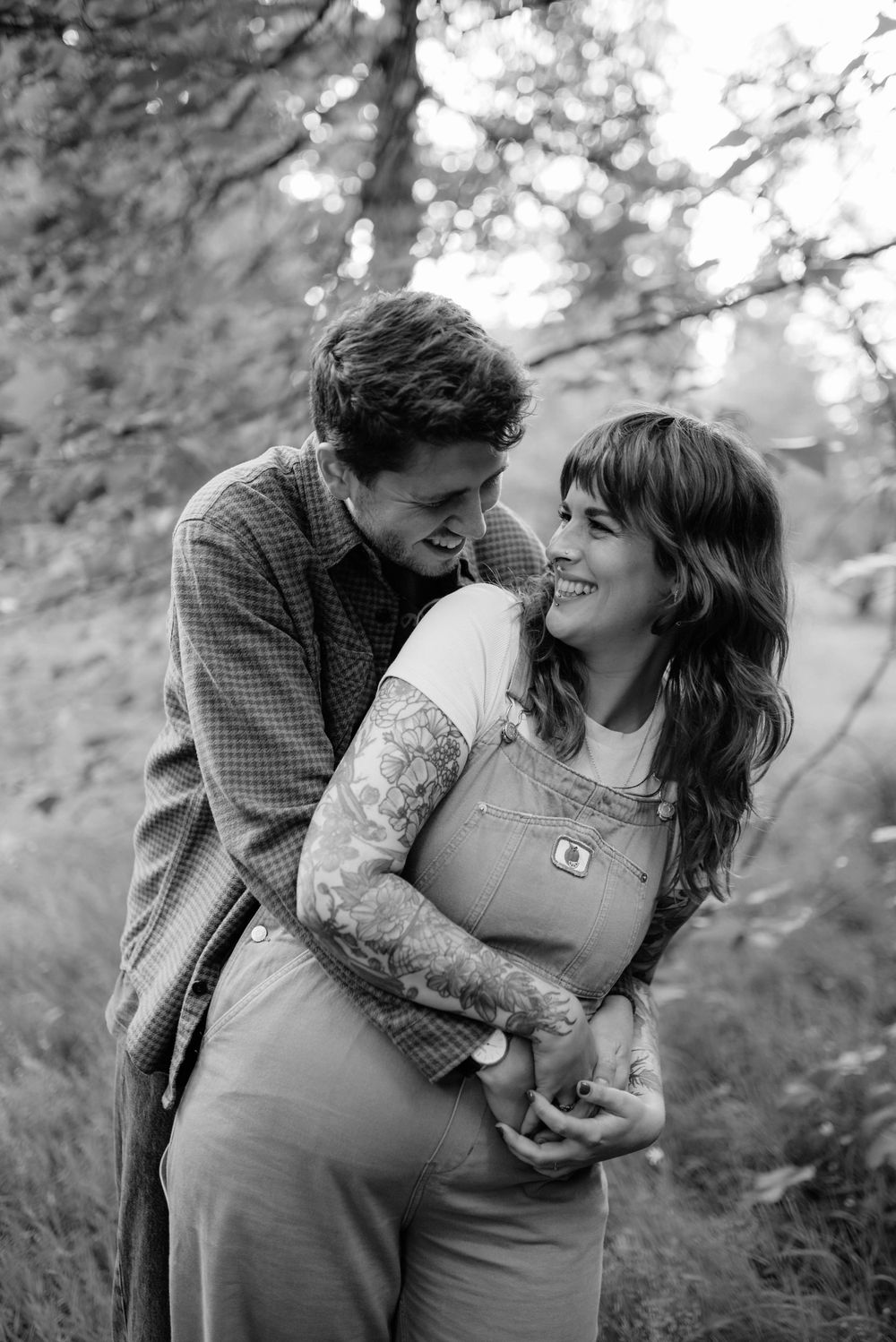 A romantic black and white photo shows an intimate moment between a couple embracing outdoors.