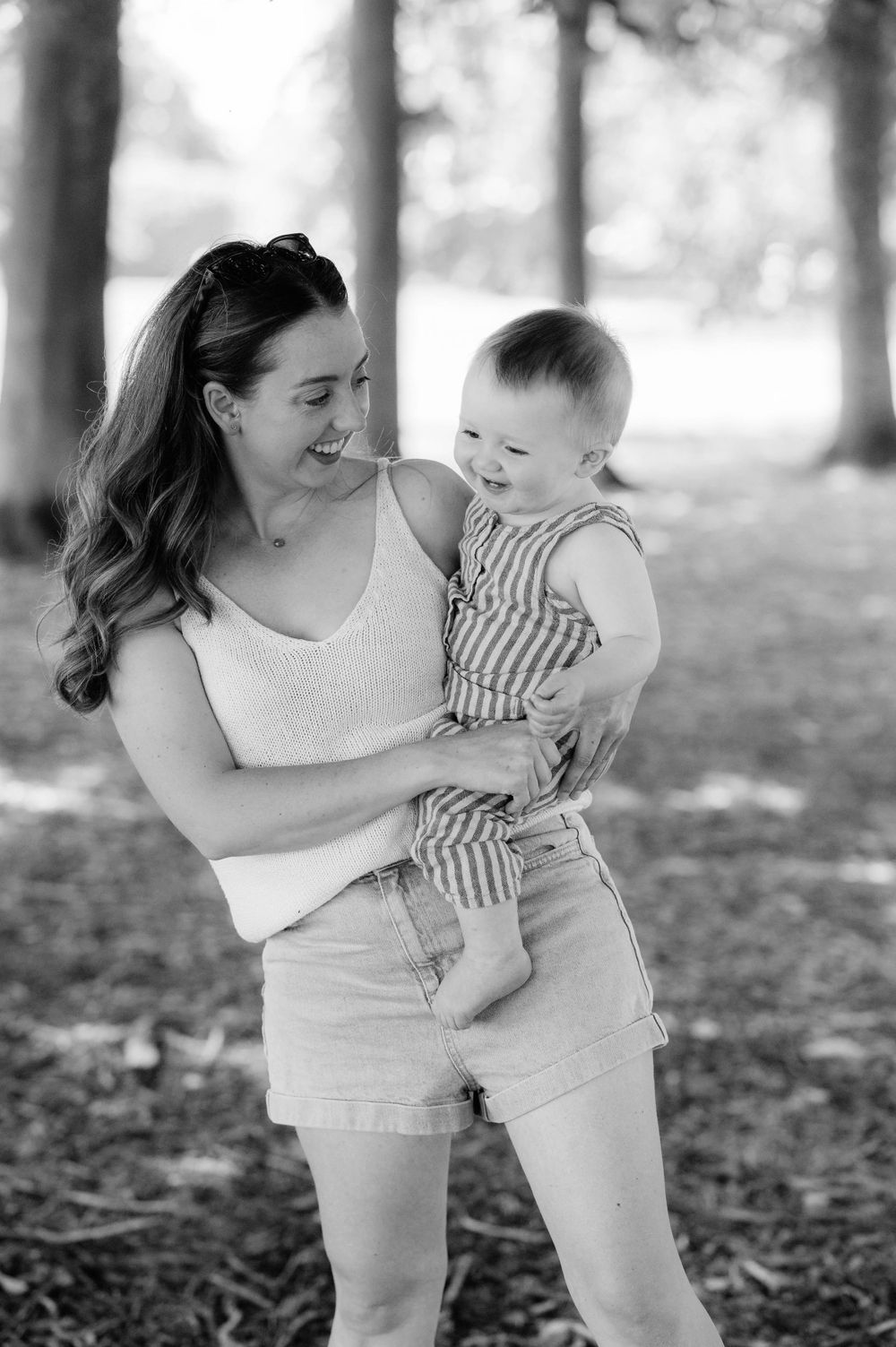 A joyful outdoor moment between parent and baby wearing striped overalls.