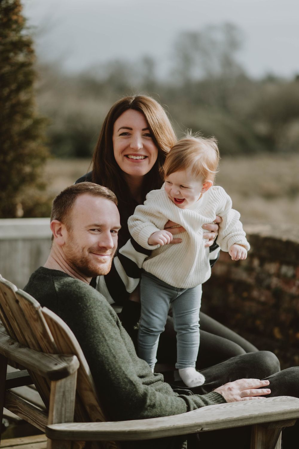 A cheerful family moment outdoors on a wooden bench in casual winter clothing.