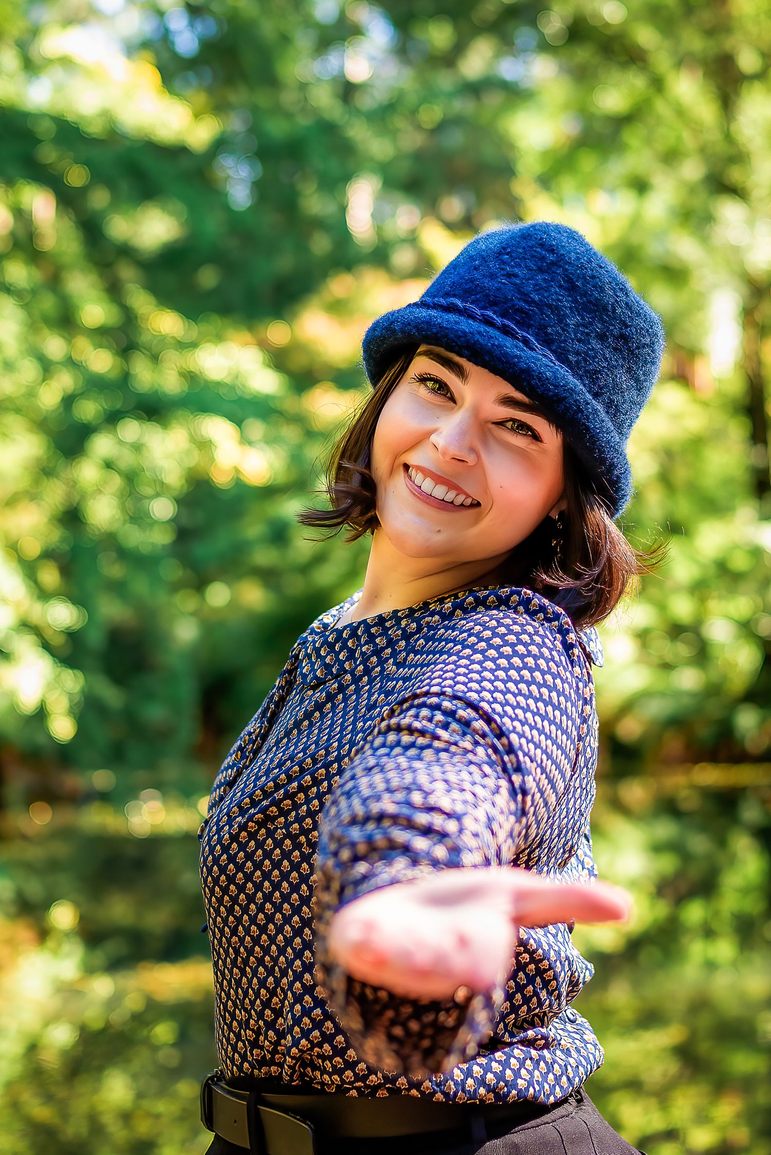Female in blue hat gesturing towards the camera while smiling in Melbourne.